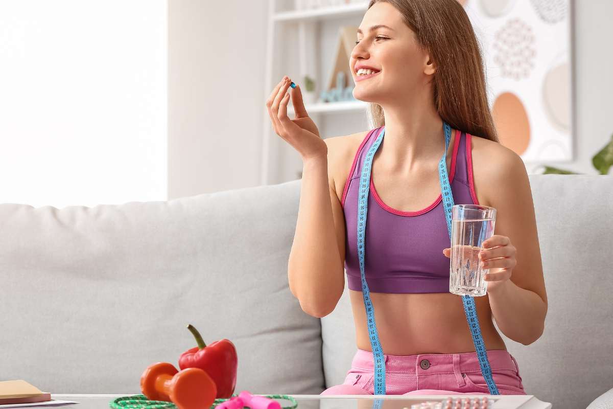 Una ragazza in tenuta da fitness con metro da sarta e bicchiere d'acqua