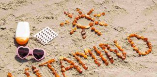 Scritta Vitamin D sulla sabbia con occhiali da sole
