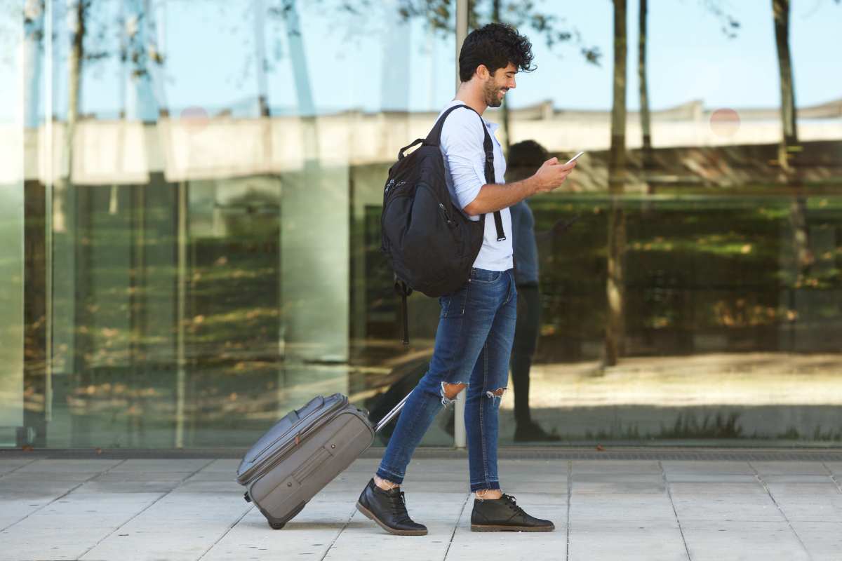 Ragazzo porta un trolley e guarda il cellulare