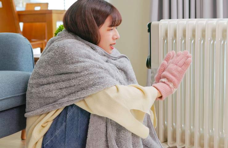 Una ragazza con scialle e guanti davanti ad un termosifone