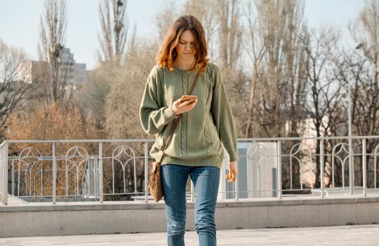 Una ragazza cammina guardando il telefonino